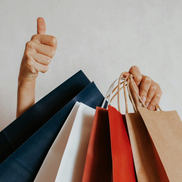 person holding shopping bags with a thumbs up