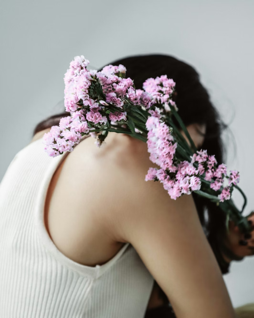 Flowers held over a person's shoulder in what looks like a self-embrace to reflect learning how to forgive