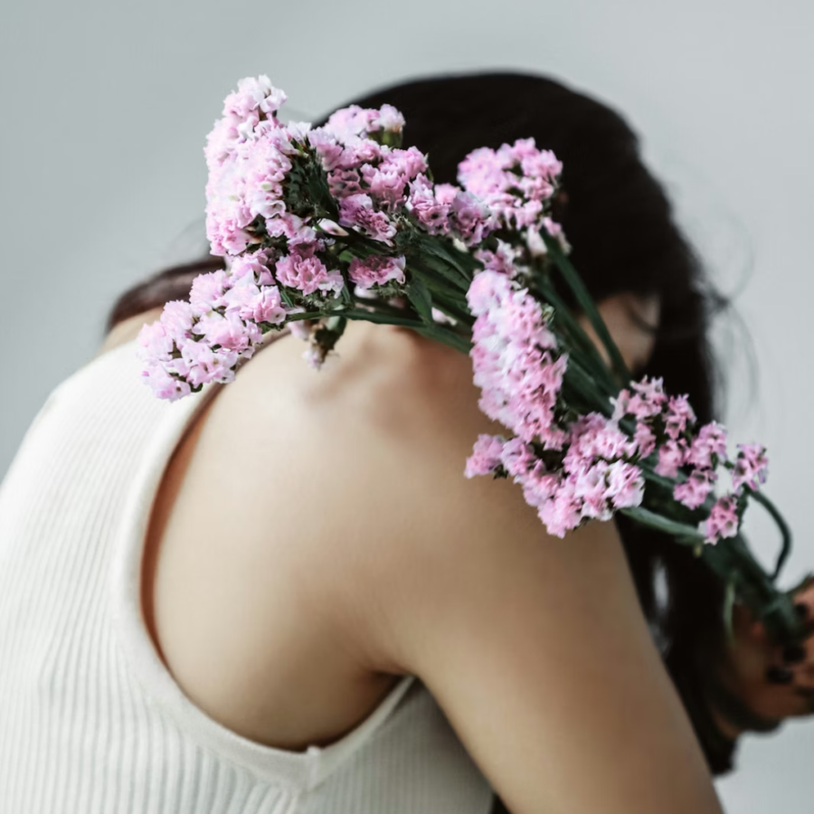 Flowers held over a person's shoulder in what looks like a self-embrace to reflect learning how to forgive