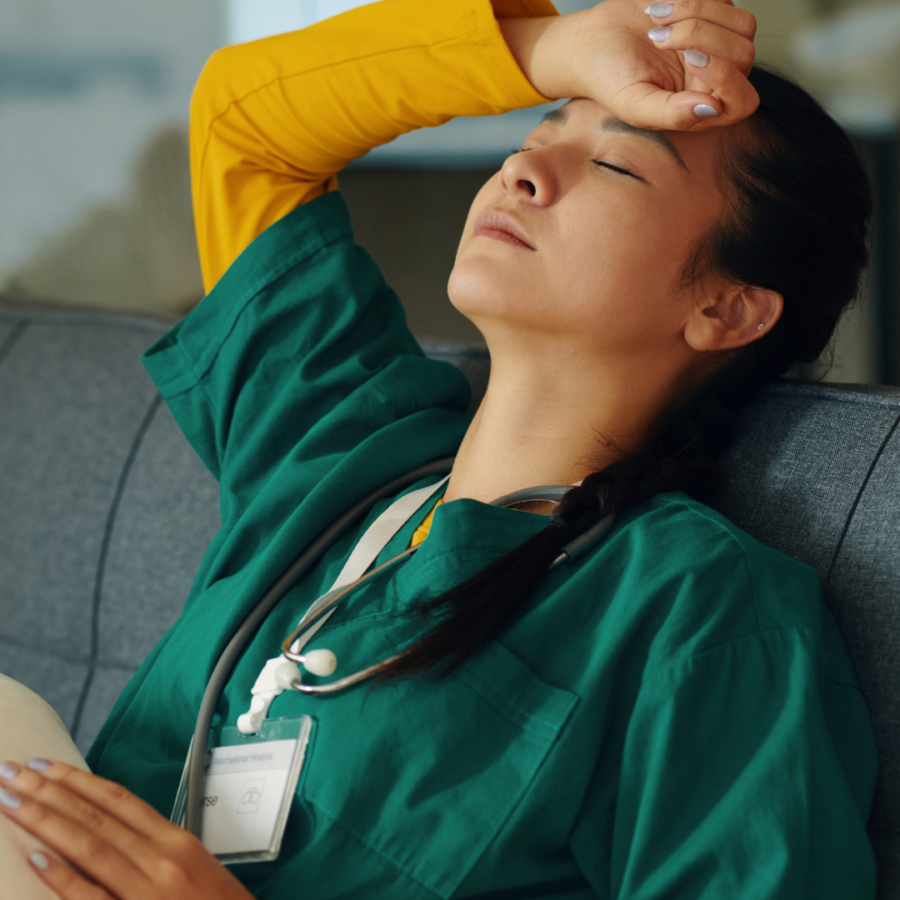 Person in medical scrubs resting on a couch, learning to practice self-care.